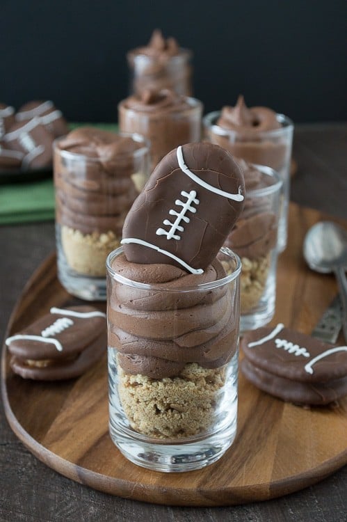 Chocolate cheesecake football dessert shooters topped with peanut butter stuffed chocolate footballs. A great recipe for game day!