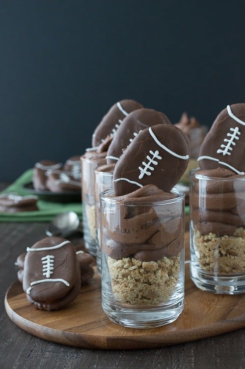 Chocolate cheesecake football dessert shooters topped with peanut butter stuffed chocolate footballs. A great recipe for game day!