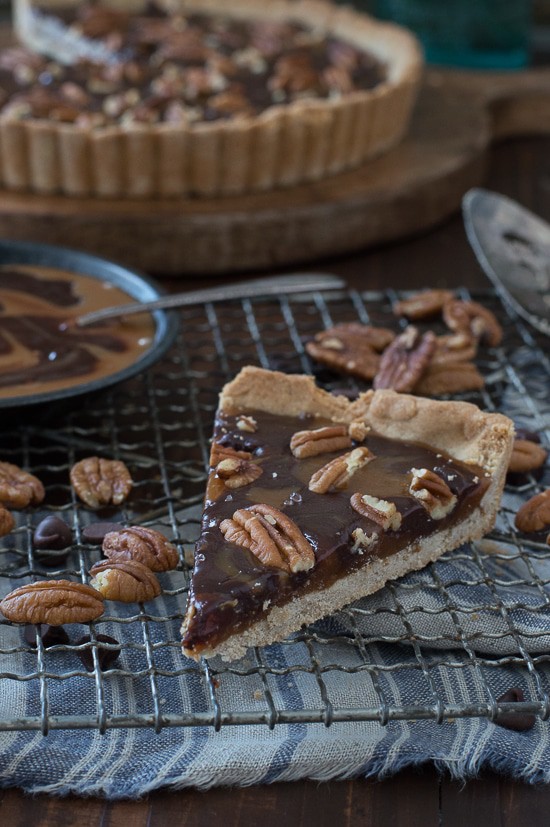 This turtle tart is swirled with caramel and chocolate then topped with pecans and sea salt! 