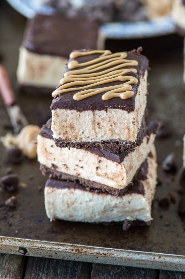 No bake buckeye bar recipe with a chocolate crust, creamy peanut butter filling, and topped with chocolate ganache. Serve them chilled or frozen! 
