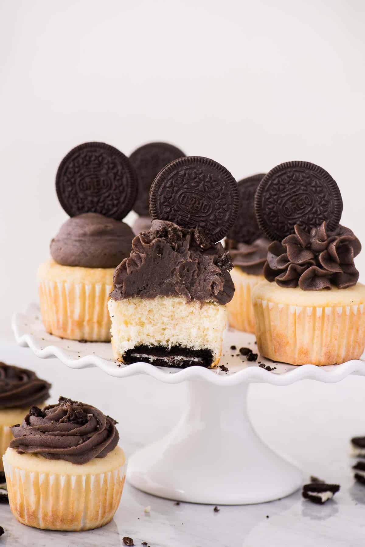 vanilla oreo bottom cupcakes on white cake stand on white background