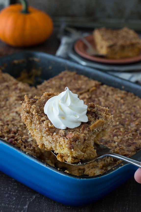 slice of pumpkin dump cake on metal spatula with blue cake pan in the background