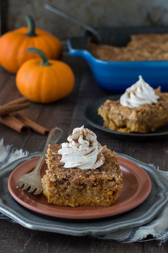 Delicious slice of Pumpkin Dump Cake with whipped cream on a brown serving plate with a silver fork.