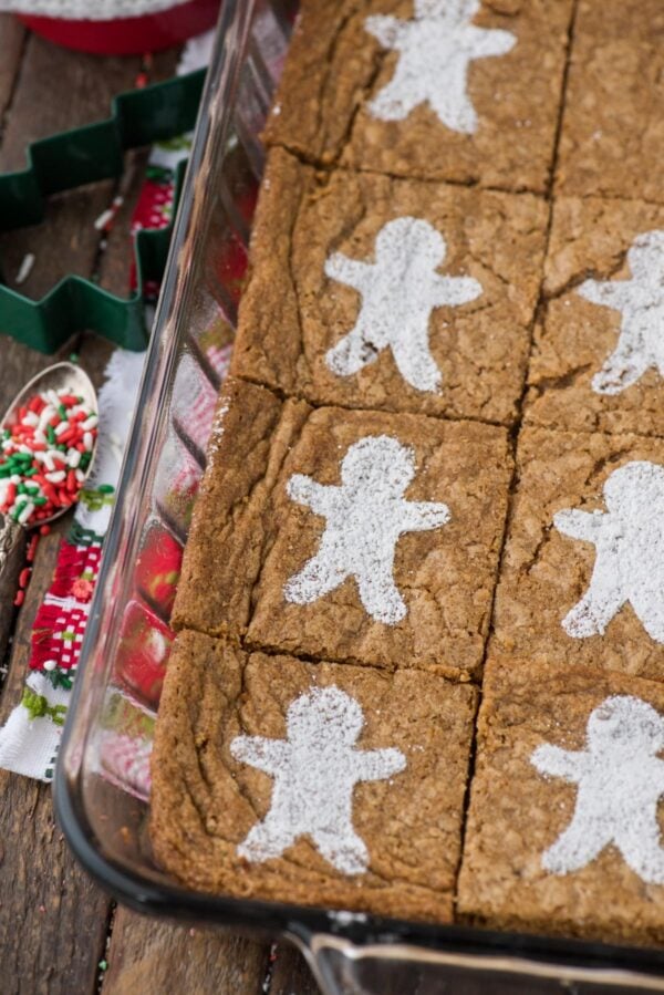 gingerbread brownies dusted with powdered sugar gingerbread men in glass 9x13 inch pan on wood background