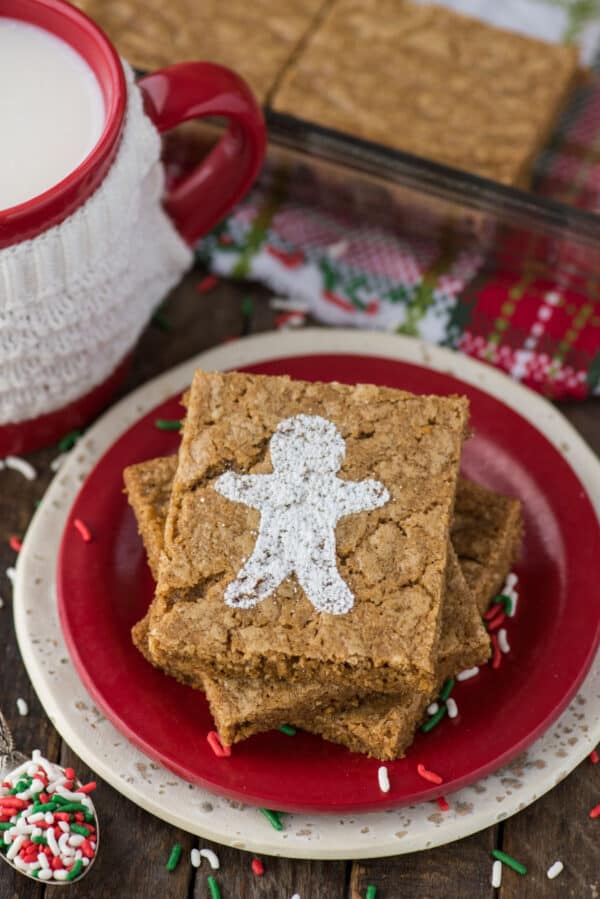 gingerbread brownies dusted with powdered sugar gingerbread men on red plate on wood background