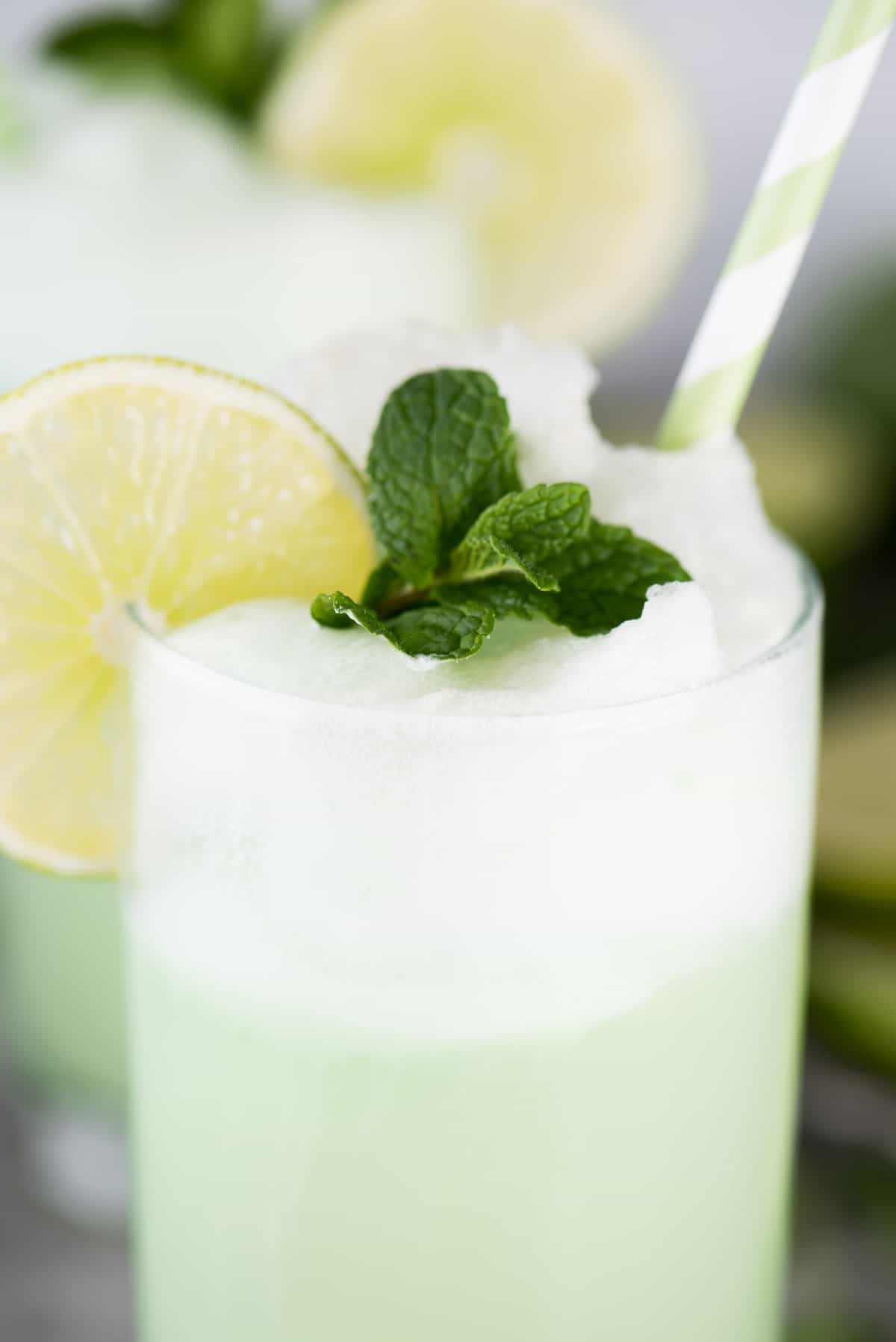 lime sherbet float in glass cup with lime slice, mint leaves and green straw