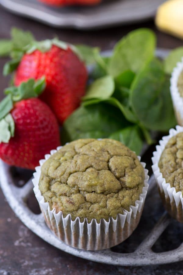 HEALTHY GREEN MONSTER SMOOTHIE MUFFINS full of spinach, strawberries and banana! Estimated to be 95 calories per muffin! Great muffin to sneak in vegetables for kids! Delicious Green Monster Smoothie Muffins with strawberries and spinach on a cooling rack.