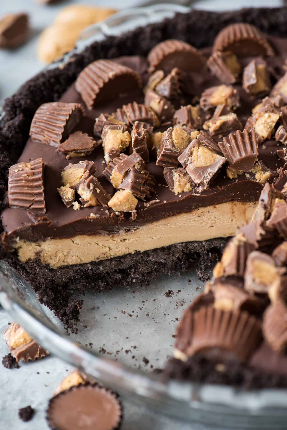 chocolate peanut butter pie with reese’s cups in glass pie pan with slice of pie removed