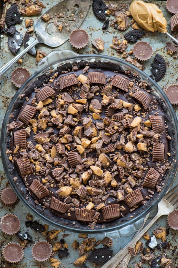 chocolate peanut butter pie with reese's cups in glass pie pan on metal background