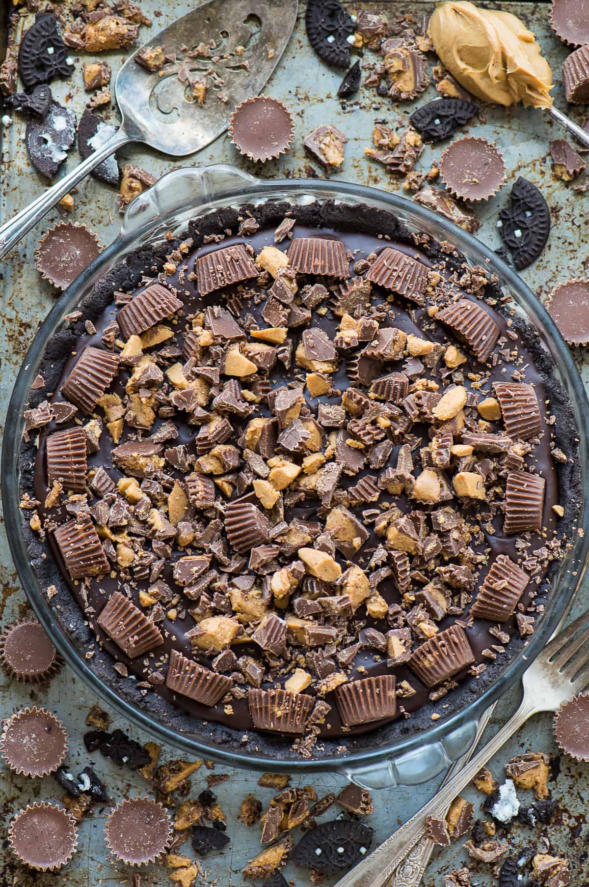 chocolate peanut butter pie with reese's cups in glass pie pan on metal background
