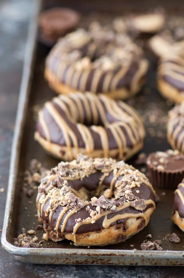 Love peanut butter cups? Make homemade donuts stuffed with peanut butter cups, topped with chocolate ganache and peanut butter drizzle. Stuffed Peanut Butter Cup Donuts! 