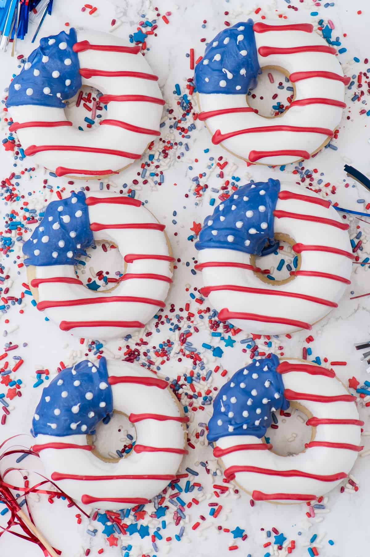 baked vanilla donuts with american flag pattern on white background with 4th of july sprinkles