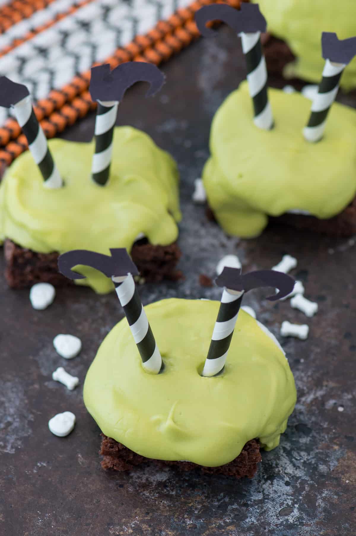 brownie square with green chocolate dripping over the side with striped witch's legs with black shoes stuck upside down in the chocolate