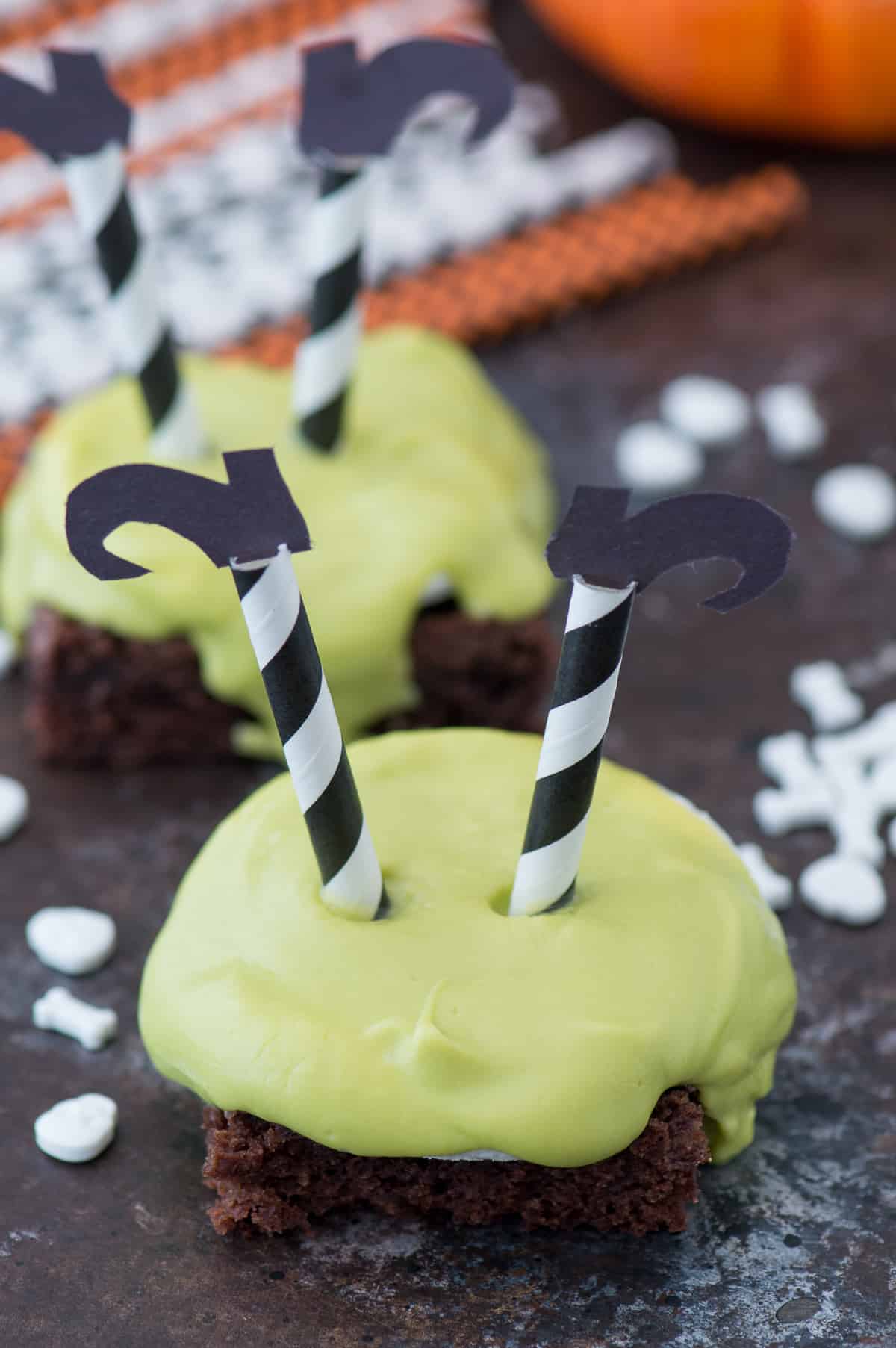 brownie square with green chocolate dripping over the side with striped witch's legs with black shoes stuck upside down in the chocolate