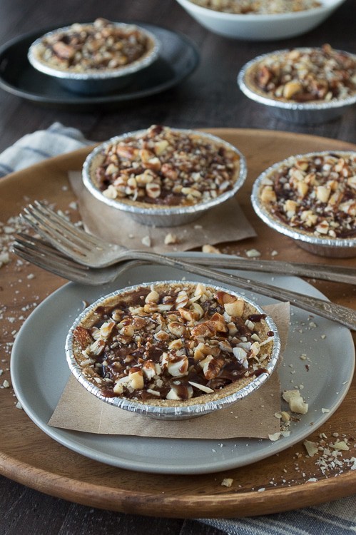 No bake mini pies with 2 layers of mixed nuts and a rich chocolate filling, all topped with chocolate and caramel!