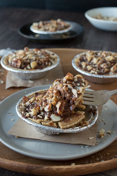 No bake mini pies with 2 layers of mixed nuts and a rich chocolate filling, all topped with chocolate and caramel!
