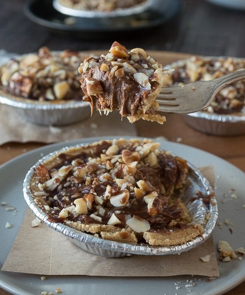 No bake mini pies with 2 layers of mixed nuts and a rich chocolate filling - top them with chocolate and caramel!