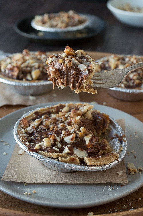 No bake mini pies with 2 layers of mixed nuts and a rich chocolate filling, all topped with chocolate and caramel!