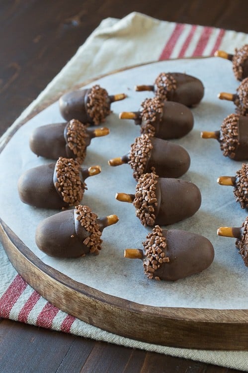 Adorable and delicious oreo acorn ball desserts on a round wooden board.