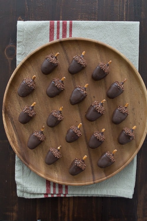 Eighteen EASY Peanut butter oreo balls on a wooden board on top of a white cloth with four thin red stripes.