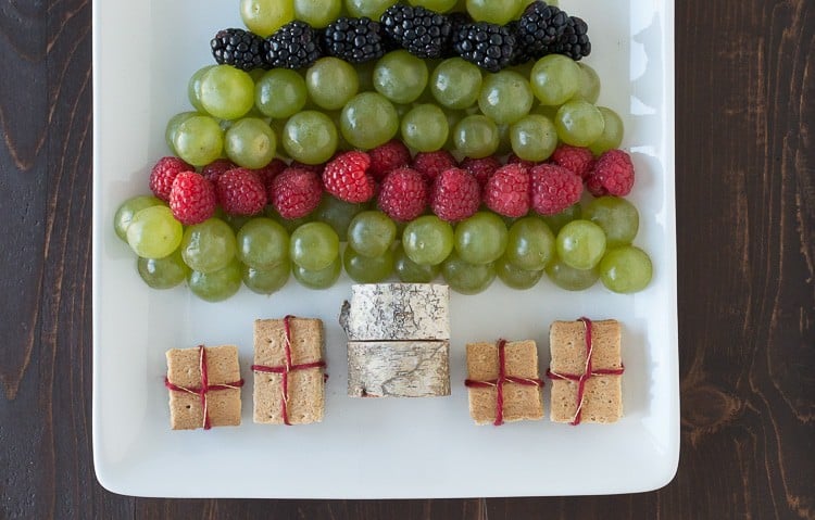 green grapes, raspberries and blackberries arranged to look like a Christmas tree on white platter