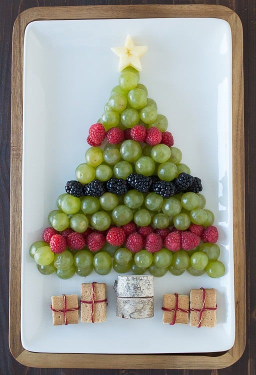 green grapes, raspberries and blackberries arranged to look like a Christmas tree on white platter