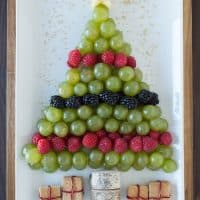 Create a healthy fruit platter for Christmas in the shape of a christmas tree using an apple, grapes, raspberries, blackberries, and graham crackers!