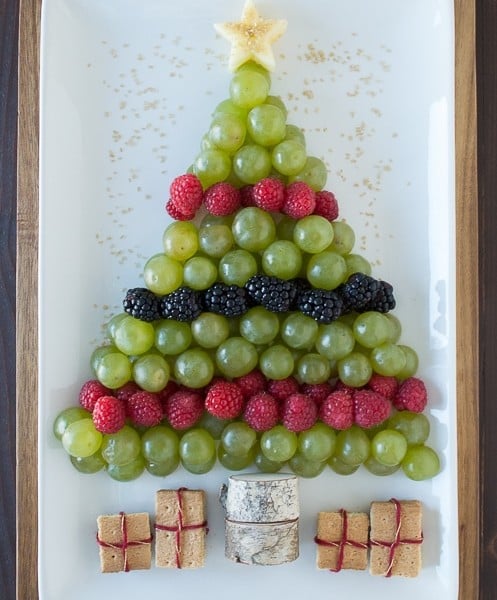 Create a healthy fruit platter for Christmas in the shape of a christmas tree using an apple, grapes, raspberries, blackberries, and graham crackers!