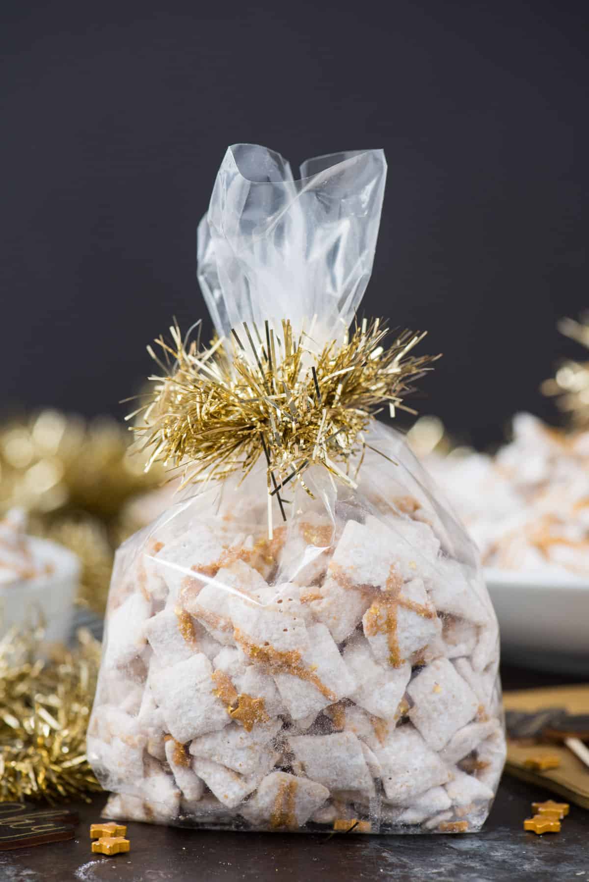 new year’s eve white chocolate puppy chow with gold sprinkles and gold stars inside a cellophane bag with gold ribbon