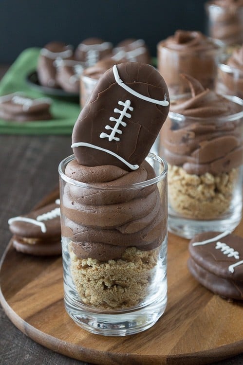 Chocolate cheesecake football dessert shooters topped with peanut butter stuffed chocolate footballs. A great recipe for game day!