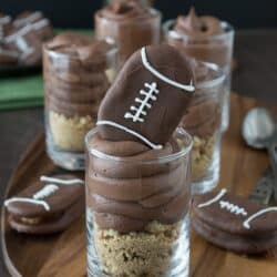 Chocolate cheesecake football dessert shooters topped with peanut butter stuffed chocolate footballs! A great recipe for game day!