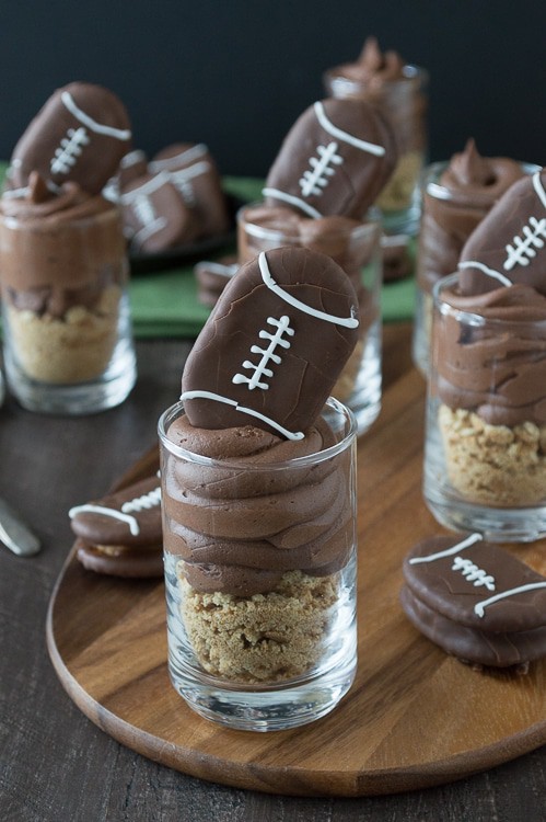 Chocolate cheesecake football dessert shooters topped with peanut butter stuffed chocolate footballs. A great recipe for game day!