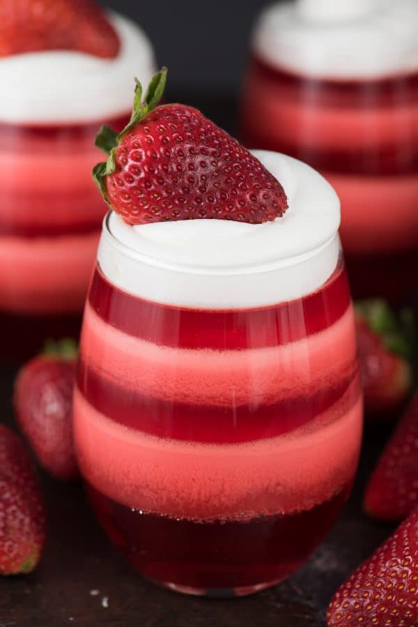Strawberry Jello layered in glass Cups topped with whipped cream 