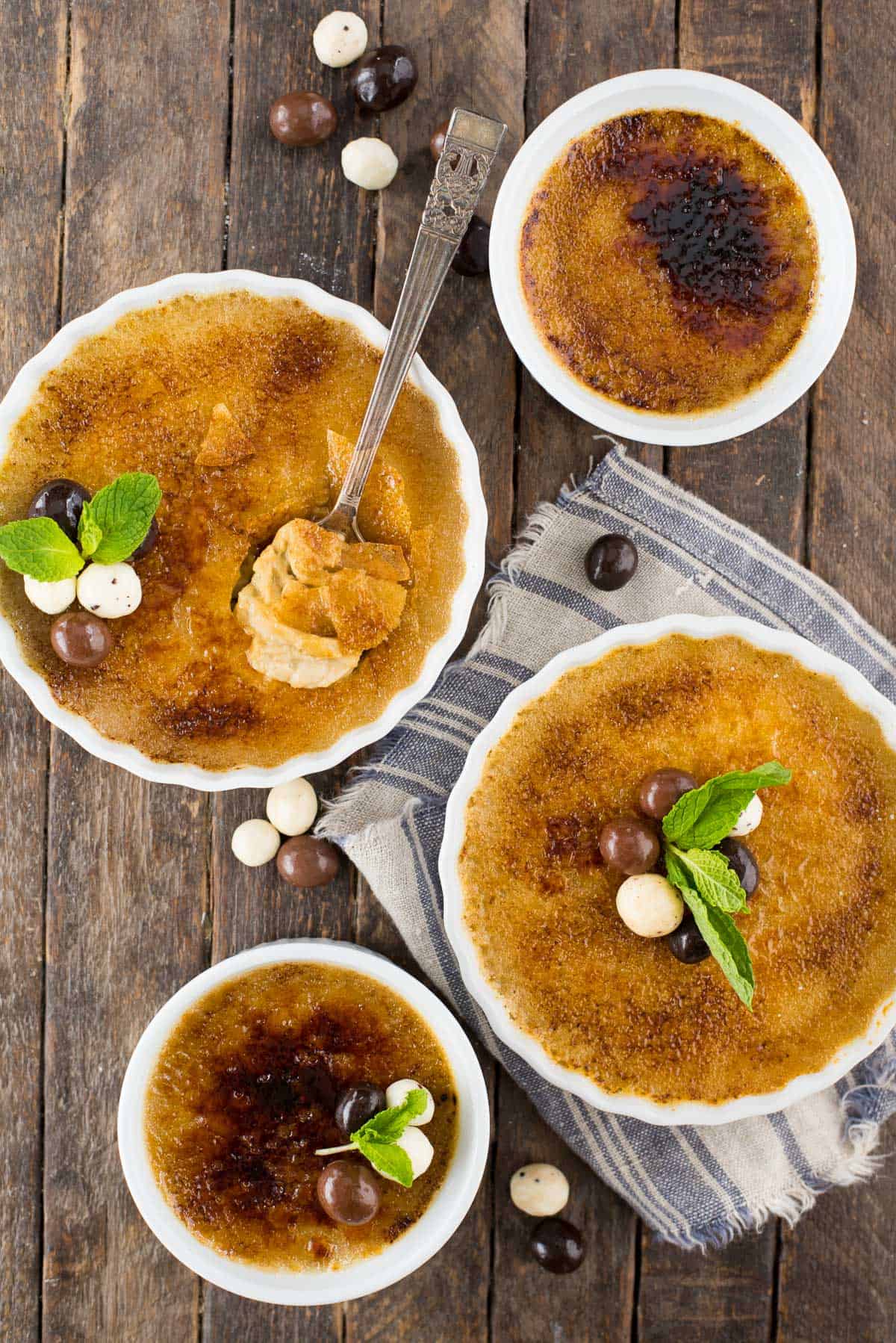 espresso creme brûlée in white round ramekin with chocolate covered coffee beans and mint leaf on top of creme brûlée
