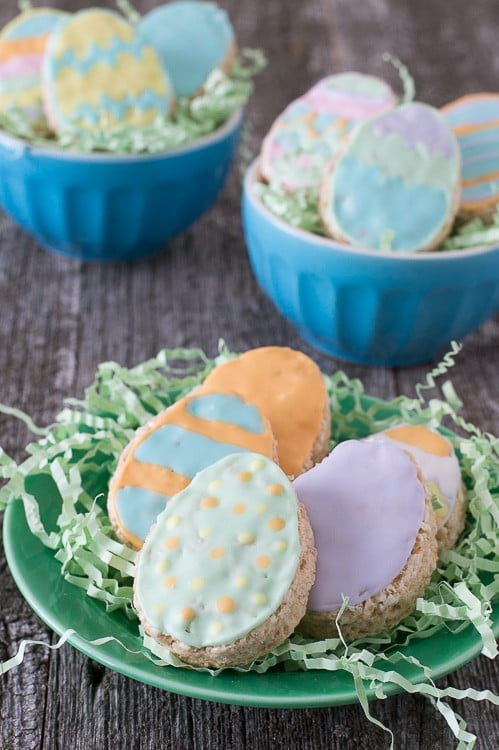 Five Rice Krispies Easter Eggs with colorful royal icing on a green serving plate on a wooden table.