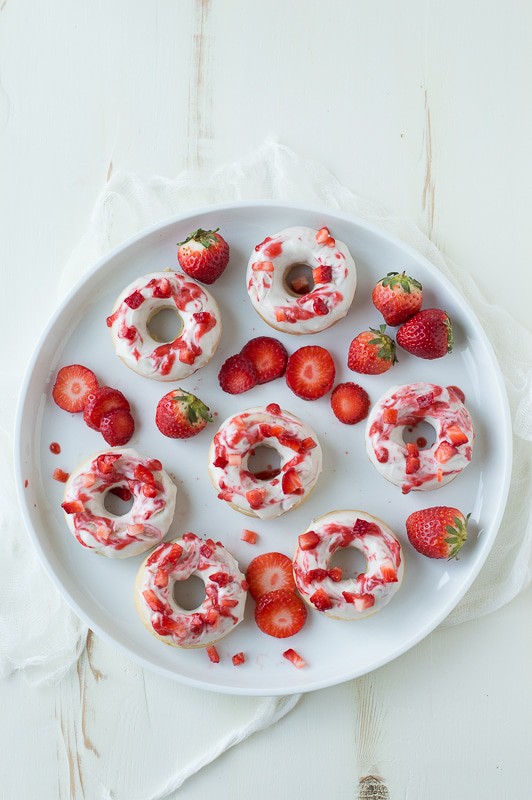 Strawberry Cheesecake Donuts with strawberries in the batter, topped with a cream cheese glaze and strawberry coulis. 