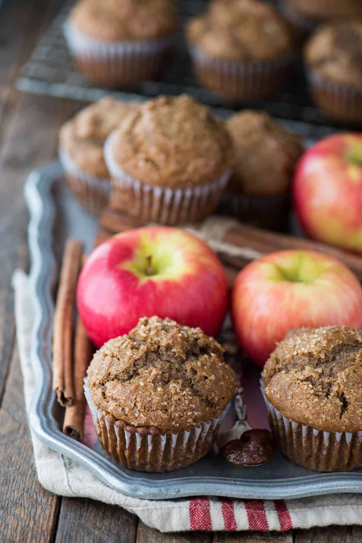 apple butter muffins on metal serving tray with apples and tan and red striped towel