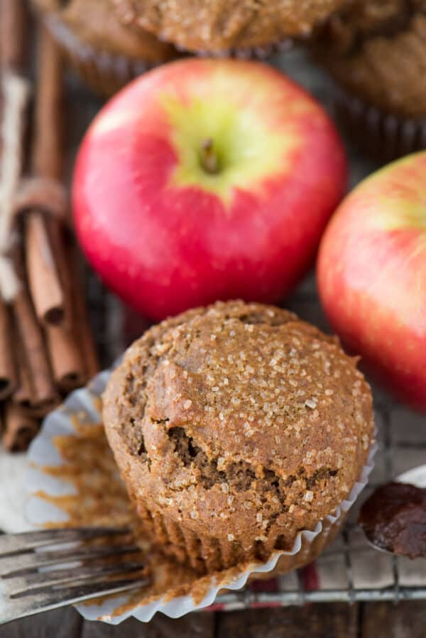 apple butter muffins on cooling rack with apples and cinnamon sticks
