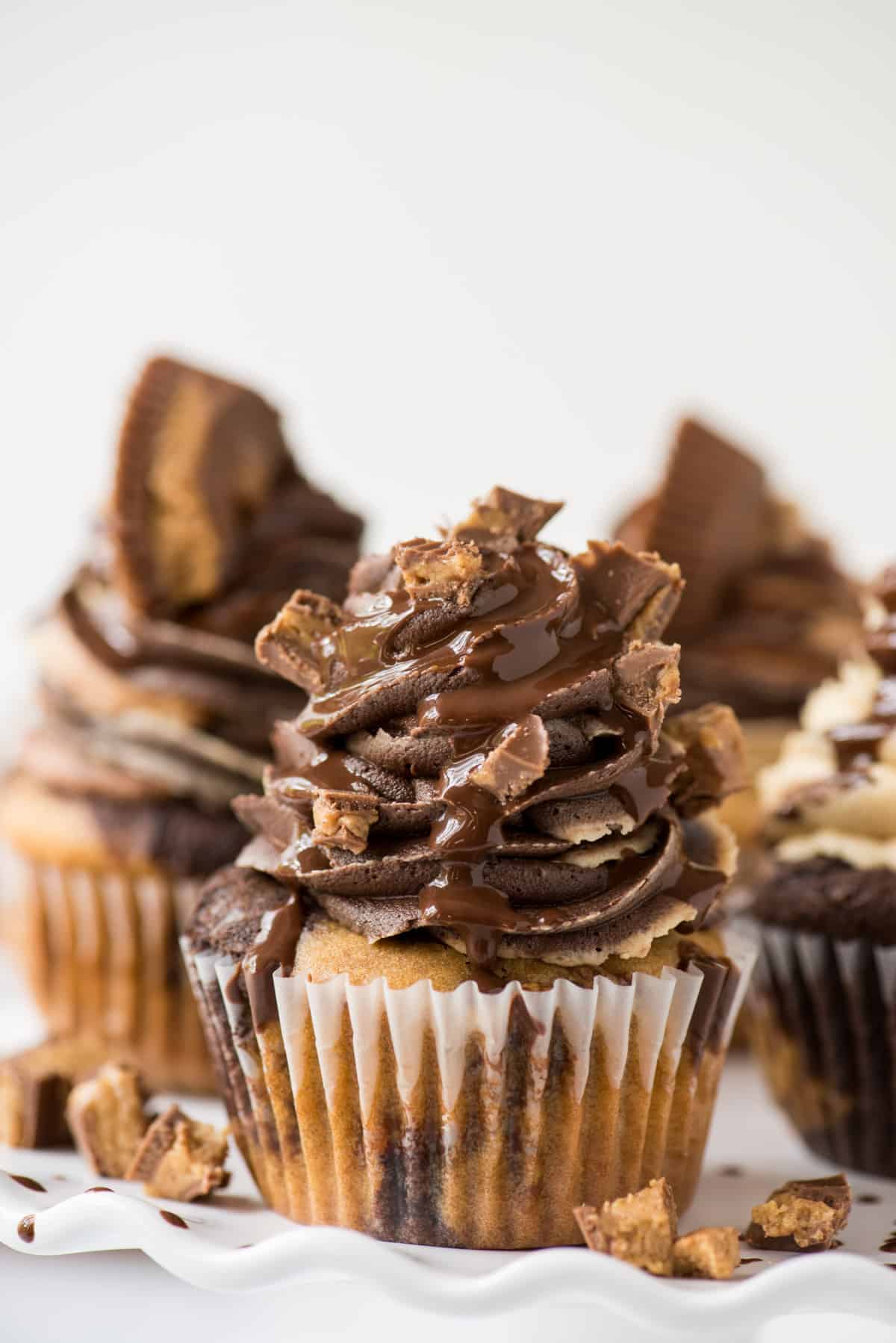 chocolate peanut butter reese’s cupcakes on white tray with white background