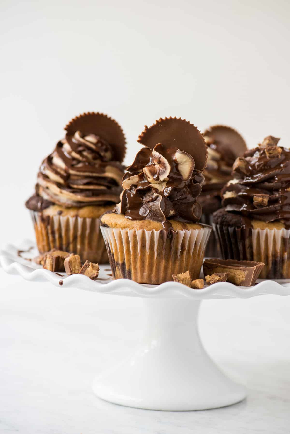 chocolate peanut butter reese’s cupcakes on white tray with white background