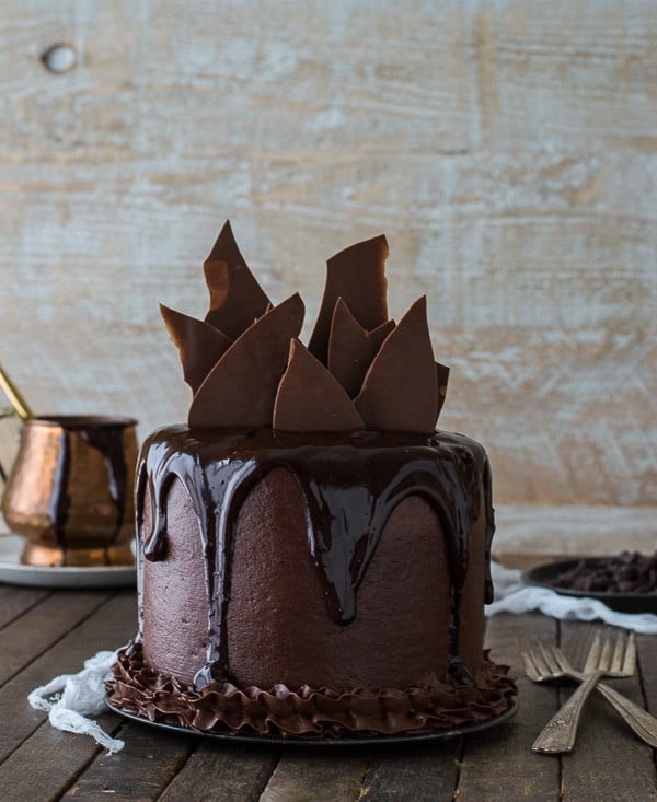 Delicious Chocolate Chocolate Cake drizzled with chocolate and chocolate frosting on a wooden table.