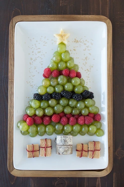green grapes, raspberries and blackberries arranged to look like a Christmas tree on white platter