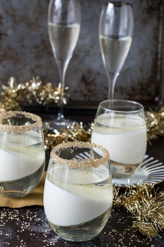 champagne jello cup shots with gold sprinkles on the glass rim on dark background