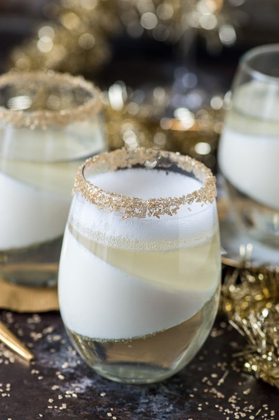  champagne jello cup shots with gold sprinkles on the glass rim on dark background
