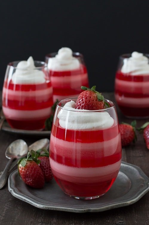 Strawberry Jello layered in glass Cups topped with whipped cream 