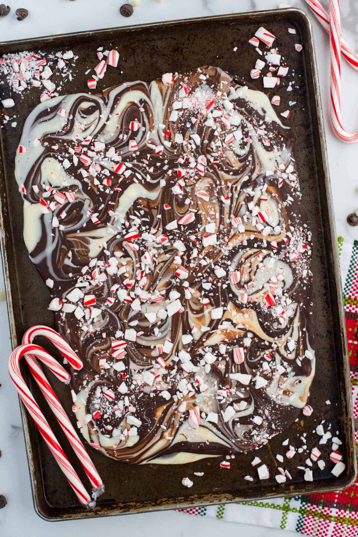 swirled chocolate and white chocolate peppermint bark on black baking sheet