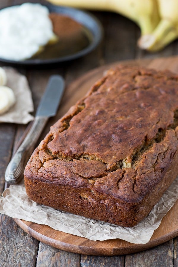 Healthier banana bread sitting on wood platter with knife