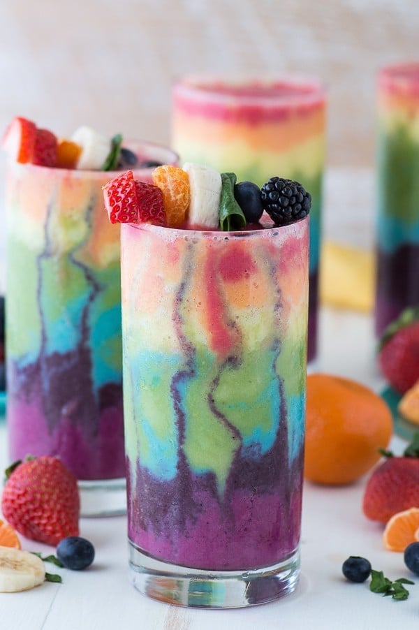 rainbow smoothie layered in glass cup with fruit on top
