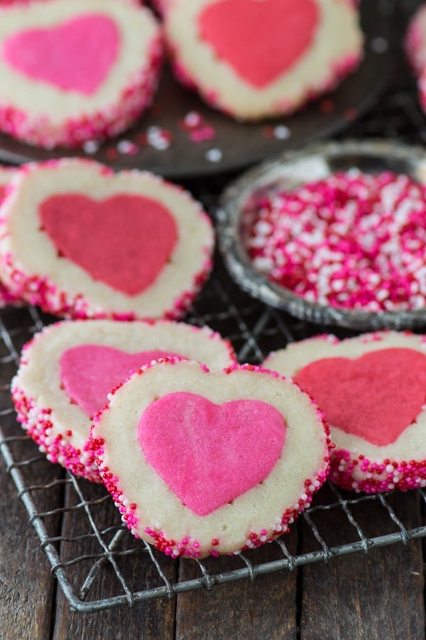 Pink and white Homemade Valentine’s Day Slice N’ Bake Cookies on a cooling rack next to pink and white sprinkles. 