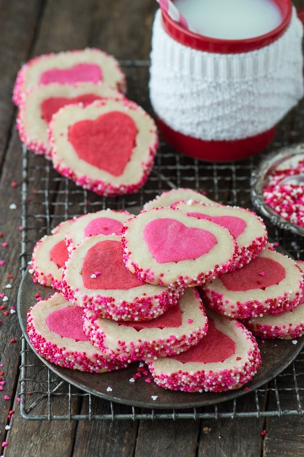 Delcious recipe of Homemade Valentine’s Day Slice N’ Bake Cookies on a cooling rack next to a red cup of milk with a pink and white stripped straw.